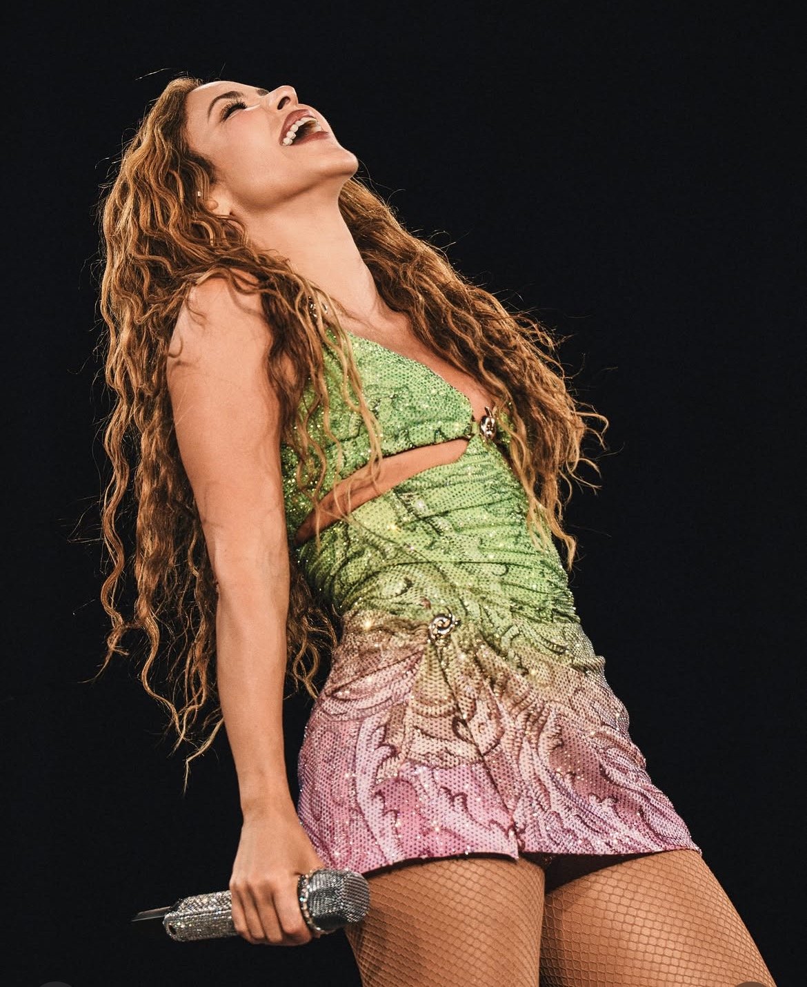 Shakira en directo durante su gira mundial 2026, look verde y rosa